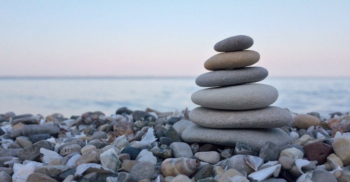 Rocks of various sizes are stacked on top of one another on a beach