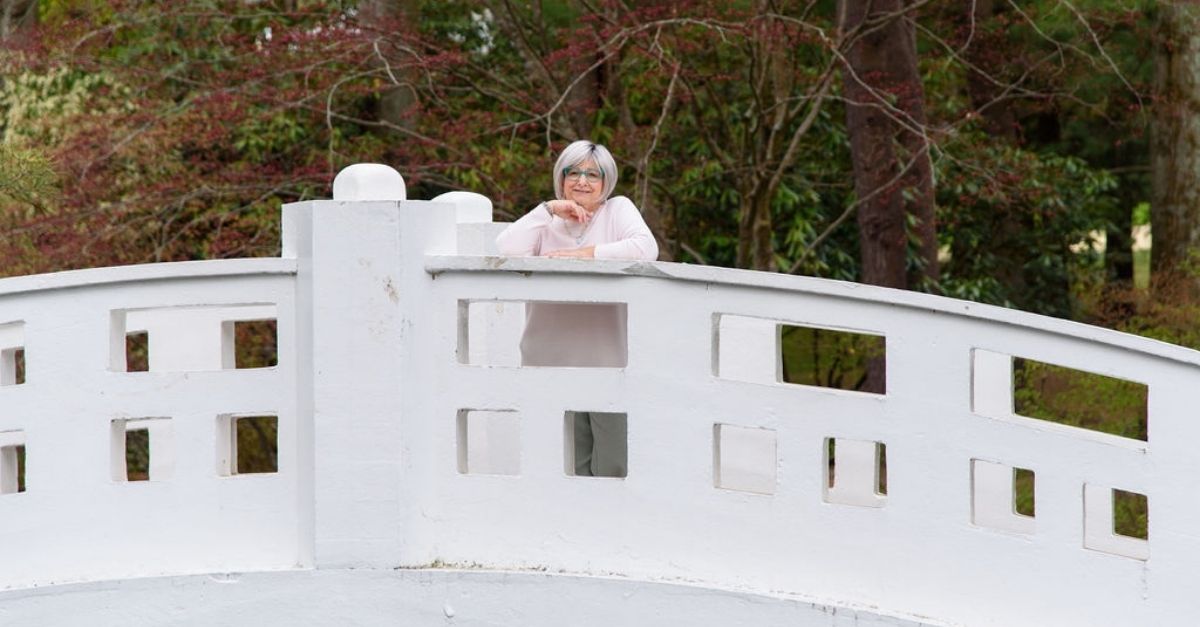 April Goff Brown stands proudly on a bridge as she looks over and smiles