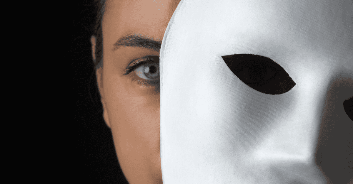Close-up of a woman’s face partly hidden behind a white mask, symbolizing the layers we hide behind and the call to authenticity in Human Design.